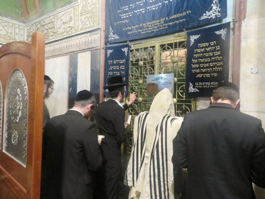 מתפללים ליד השער המוזהב ולוחות הקטיפה, בתוך מבנה המערה
