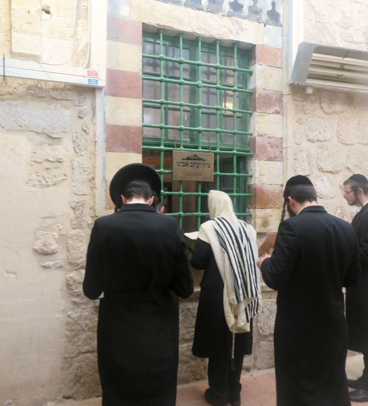 מתפללים ליד החלון המסורג, בתוך מבנה המערה